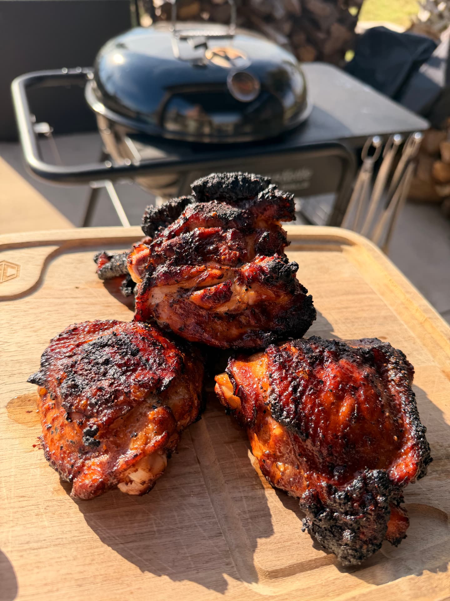 Charred grilled chicken thighs on a board